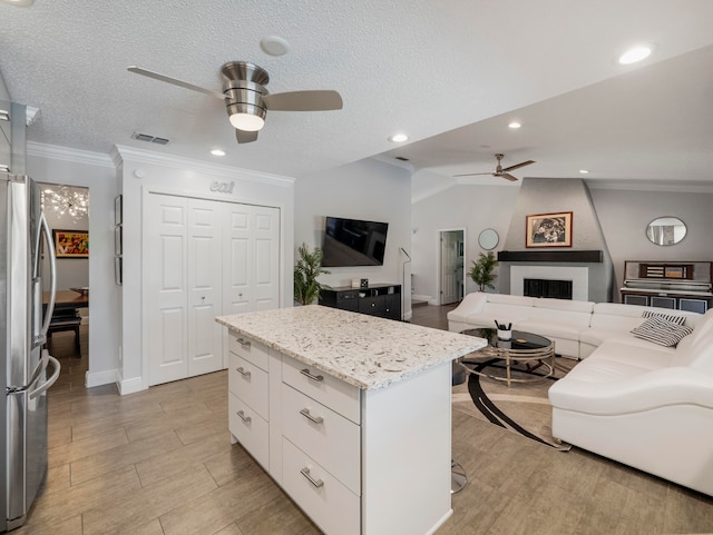 kitchen featuring white cabinetry, stainless steel refrigerator, ceiling fan, and vaulted ceiling