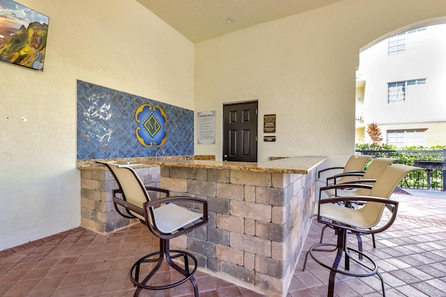 9873 Baywinds Dr Unit 5302, West Palm Beach, FL 33411 - bar featuring arched walkways, a textured wall, and a towering ceiling