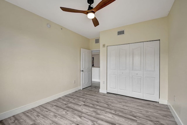 unfurnished bedroom with light wood-type flooring, ceiling fan, and a closet