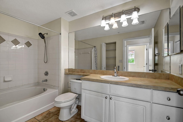 full bathroom featuring toilet, tile patterned flooring, vanity, a textured ceiling, and tiled shower / bath combo