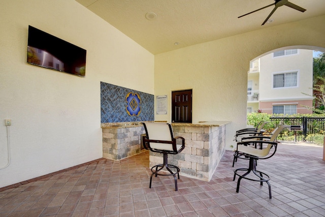 view of patio with ceiling fan and a bar