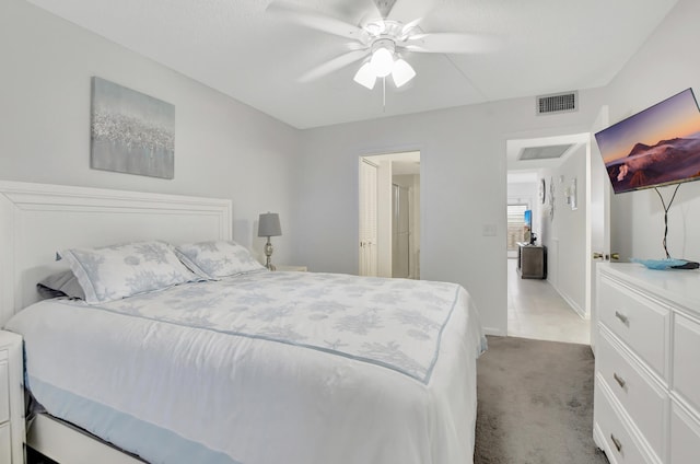 bedroom featuring a ceiling fan, visible vents, and light carpet