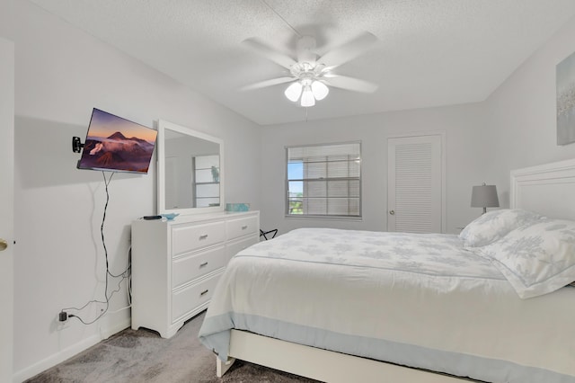 bedroom featuring a textured ceiling, ceiling fan, and light colored carpet