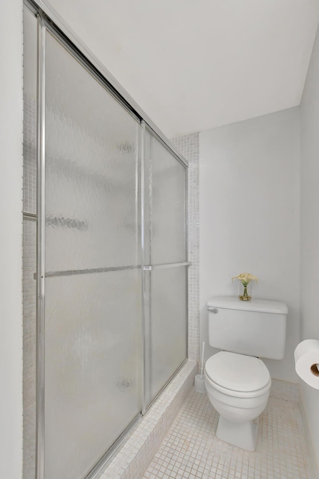 bathroom featuring tile patterned flooring, toilet, and a shower stall