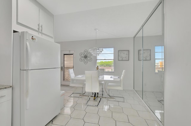 unfurnished dining area with an inviting chandelier, light tile patterned floors, and vaulted ceiling