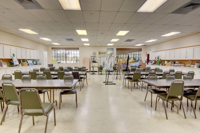 dining area with light speckled floor, a drop ceiling, and visible vents