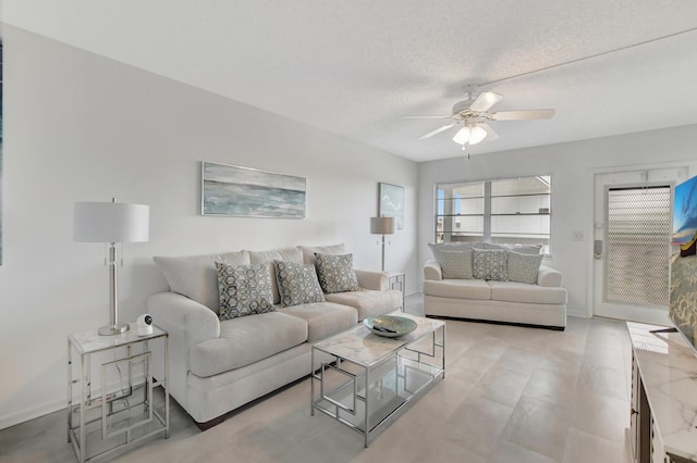 living area featuring ceiling fan, a textured ceiling, and baseboards