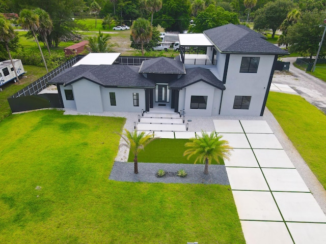 view of front of house featuring a shingled roof, a front yard, fence, and stucco siding