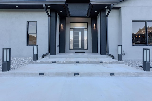 snow covered property entrance featuring stucco siding