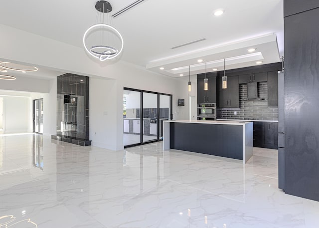 kitchen featuring light countertops, wall chimney exhaust hood, a kitchen island, and pendant lighting