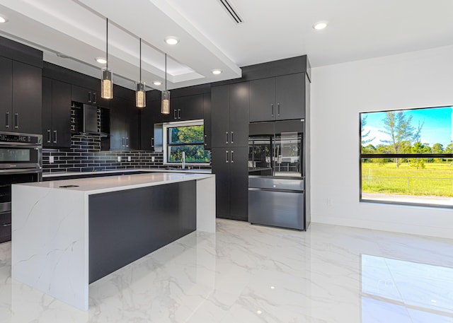 kitchen featuring a kitchen island, dark cabinets, decorative light fixtures, marble finish floor, and light countertops