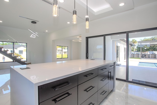 kitchen featuring marble finish floor, hanging light fixtures, a healthy amount of sunlight, and a center island