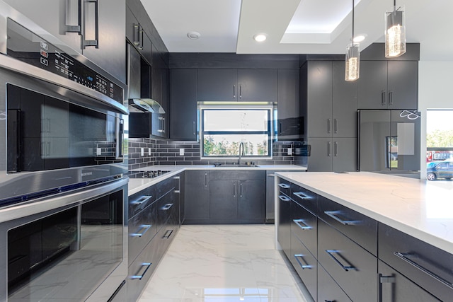 kitchen featuring dark cabinets, a sink, marble finish floor, appliances with stainless steel finishes, and pendant lighting