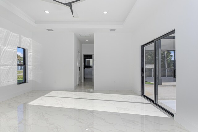 spare room featuring a healthy amount of sunlight, marble finish floor, visible vents, and a raised ceiling