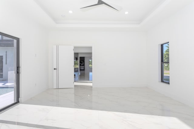 spare room featuring a tray ceiling, marble finish floor, ceiling fan, and recessed lighting