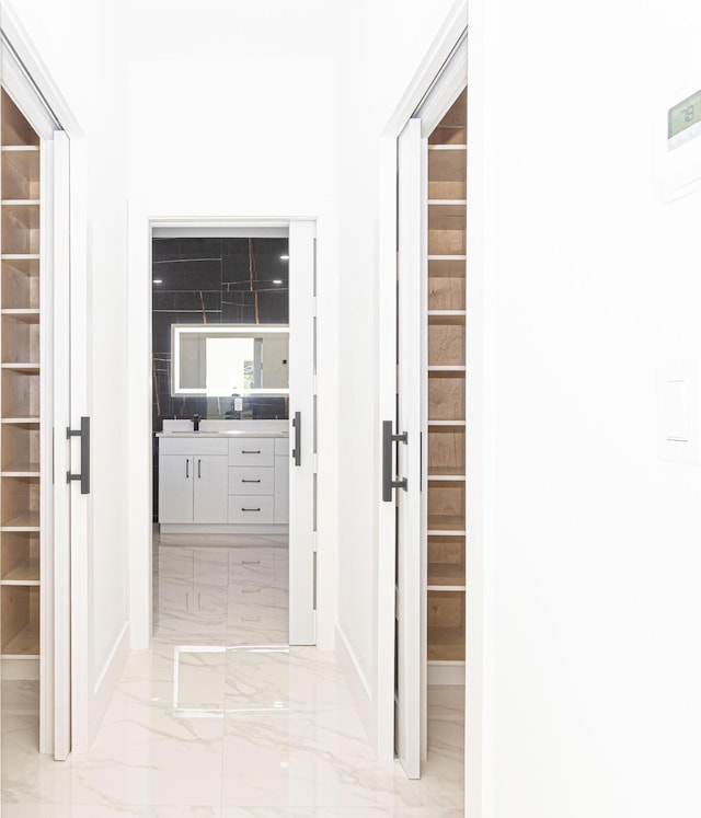 hall with marble finish floor and a sink