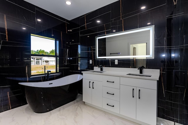 bathroom featuring a freestanding tub, a sink, tile walls, and marble finish floor