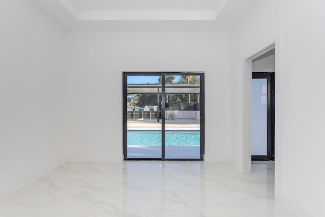 empty room with marble finish floor, baseboards, and a tray ceiling