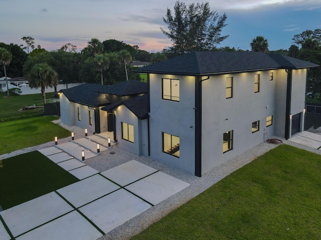 view of side of home featuring a yard, roof with shingles, a patio area, and stucco siding