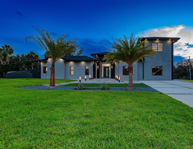 view of front of house with a front yard, fence, and stucco siding