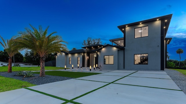 view of front of house with a front yard, a patio, and stucco siding