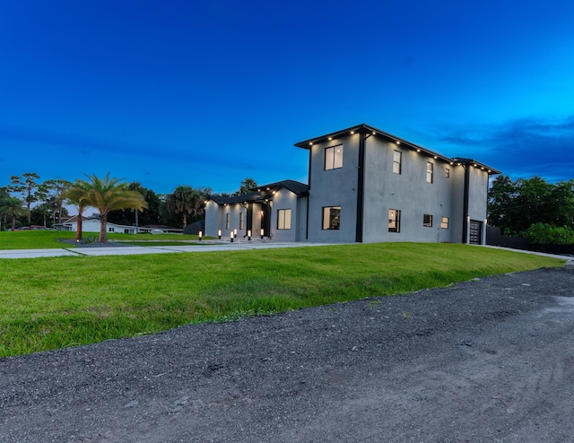 property exterior at dusk featuring a yard, driveway, an attached garage, and a pergola