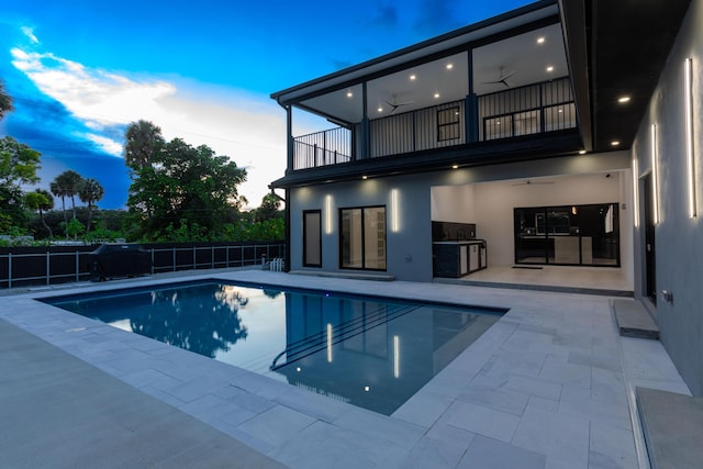 pool at dusk featuring a patio, fence, a ceiling fan, and a fenced in pool