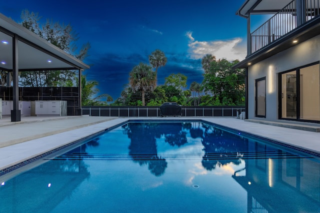 pool at dusk featuring a patio area, a grill, fence, and a fenced in pool