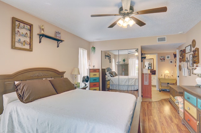 bedroom with light hardwood / wood-style floors, a closet, a textured ceiling, and ceiling fan