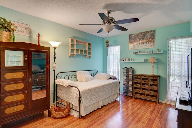 bedroom with a textured ceiling, hardwood / wood-style floors, and ceiling fan