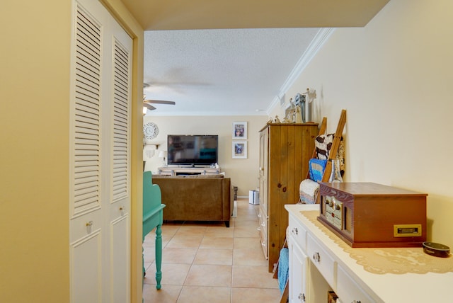 interior space featuring white cabinets, light tile patterned floors, crown molding, a textured ceiling, and ceiling fan