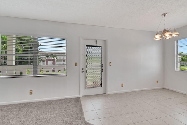 foyer with a notable chandelier, light tile patterned flooring, and a textured ceiling