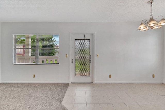 tiled entryway with a textured ceiling and an inviting chandelier