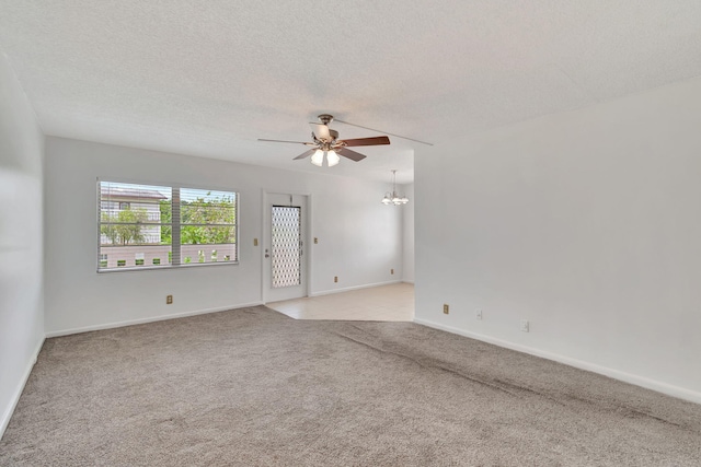 spare room featuring ceiling fan with notable chandelier, light colored carpet, and a textured ceiling