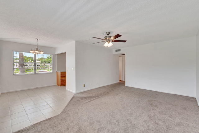 carpeted spare room with a textured ceiling and ceiling fan with notable chandelier