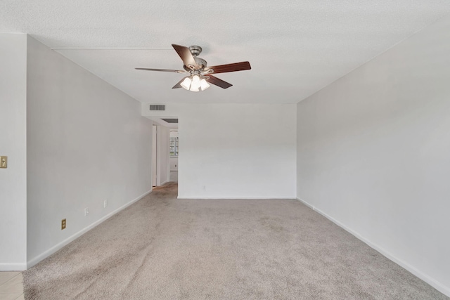 spare room with a textured ceiling, light colored carpet, and ceiling fan