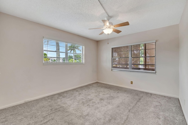 carpeted spare room with ceiling fan, a healthy amount of sunlight, and a textured ceiling