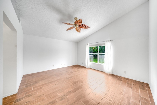 unfurnished room featuring ceiling fan, vaulted ceiling, and a textured ceiling