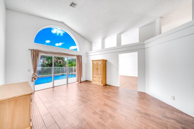 unfurnished living room with high vaulted ceiling and a textured ceiling