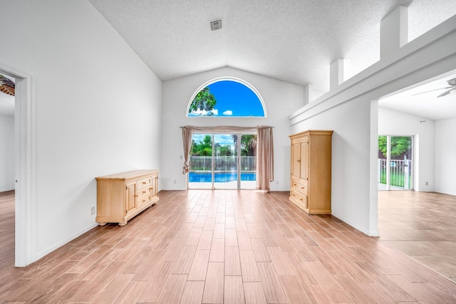 unfurnished living room featuring ceiling fan, a wealth of natural light, and high vaulted ceiling