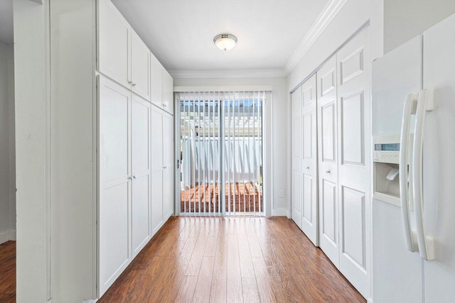 interior space with white cabinets, white fridge with ice dispenser, dark hardwood / wood-style flooring, and ornamental molding