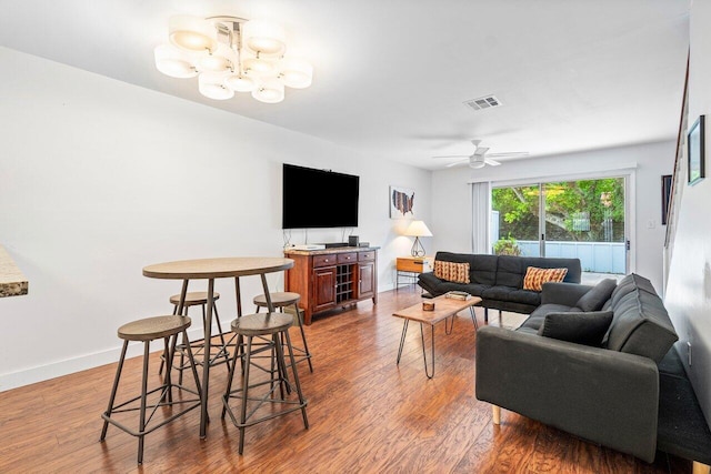 living room featuring ceiling fan with notable chandelier and hardwood / wood-style floors