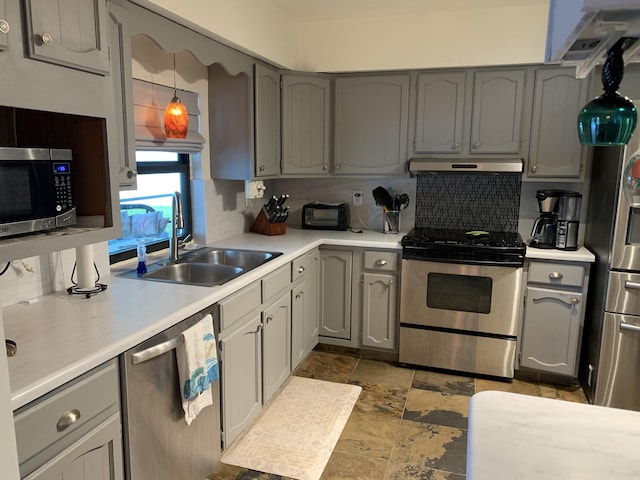 kitchen featuring sink, decorative light fixtures, appliances with stainless steel finishes, gray cabinets, and backsplash