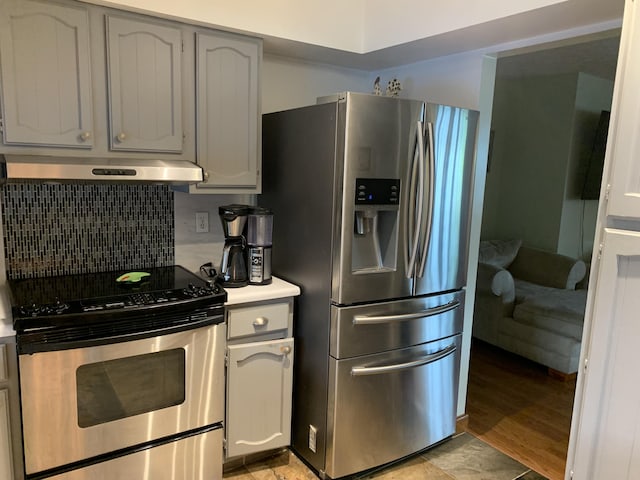 kitchen featuring extractor fan, appliances with stainless steel finishes, tasteful backsplash, gray cabinetry, and light hardwood / wood-style flooring