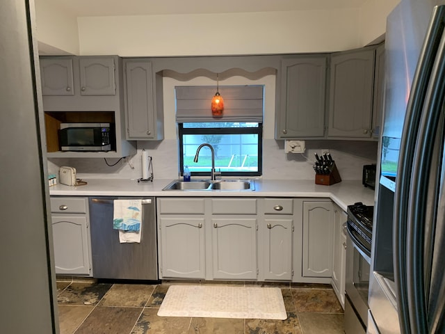 kitchen featuring pendant lighting, stainless steel appliances, gray cabinets, and sink