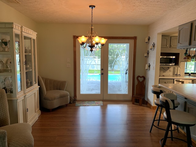 doorway to outside featuring an inviting chandelier, wood-type flooring, a textured ceiling, and french doors