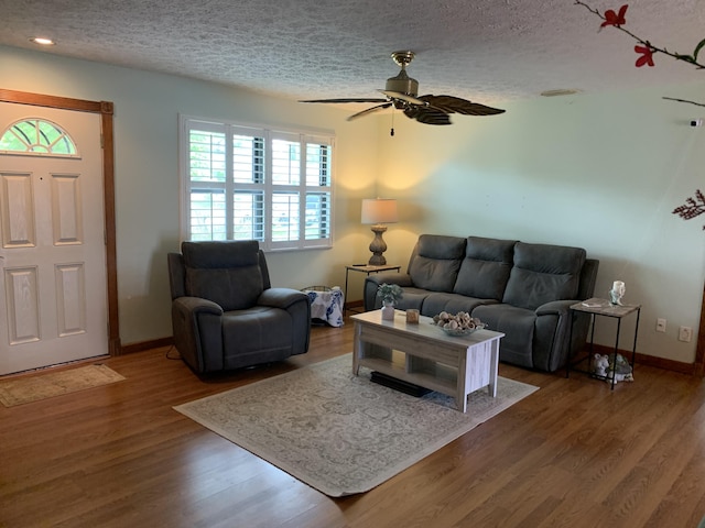 living room featuring ceiling fan, hardwood / wood-style floors, and a textured ceiling