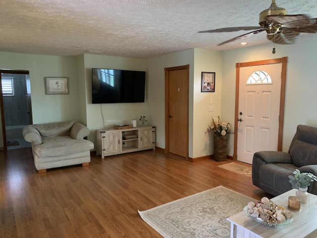 living room with ceiling fan, wood-type flooring, and a textured ceiling