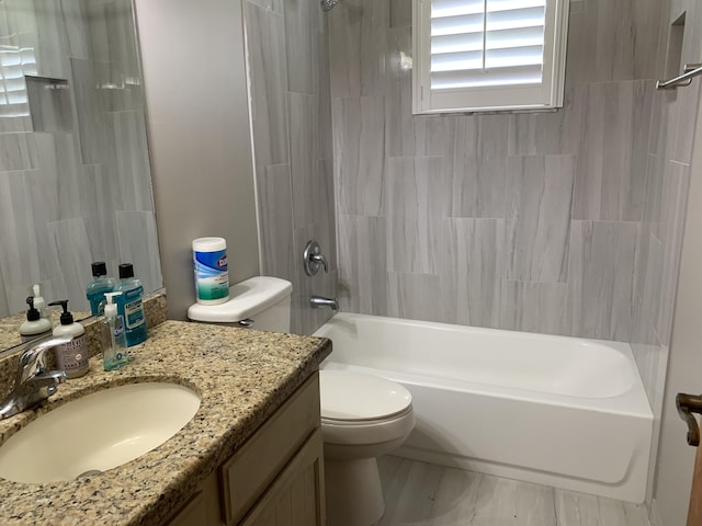 full bathroom featuring tiled shower / bath, vanity, and toilet