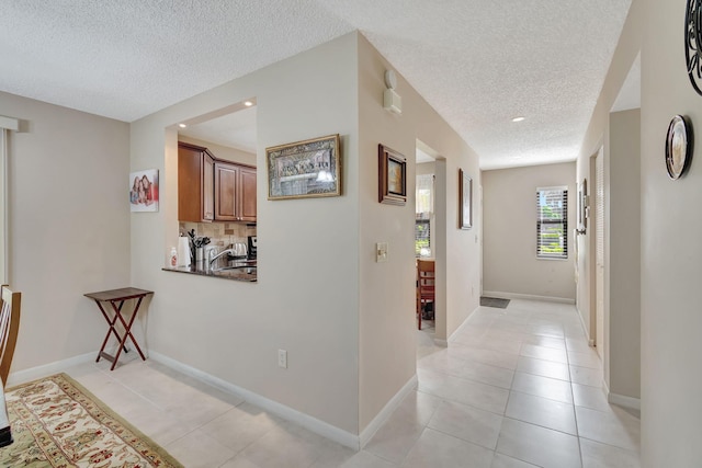 hallway with a textured ceiling and light tile patterned floors